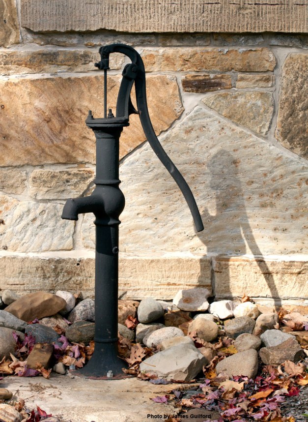 Photo: Water pump near stone wall of an old school. Photo by James Guilford.