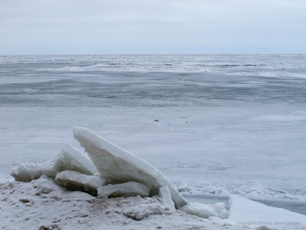 Photo: Fractured ice sheets piled on a beach. Photo by James Guilford.