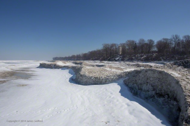 Photo: Sculpted piles of snow and ice form low cliffs along the Lake Erie Shoreline. Photo by James Guilford