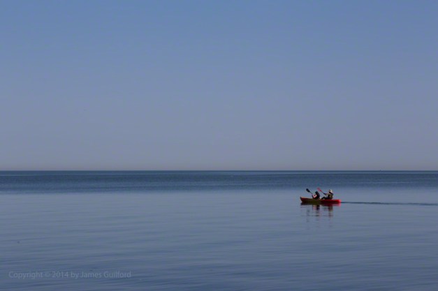Photo: Kayakers on calm Lake Erie under a blue sky. Photo by James Guilford.