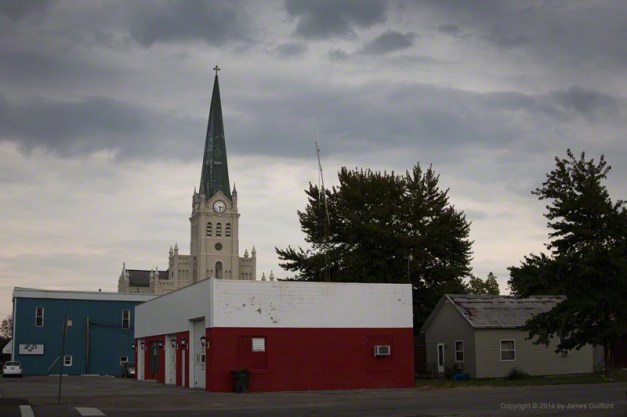 Photo: Beautiful church rises above worn-down buildings under stormy skies. Photo by James Guilford.