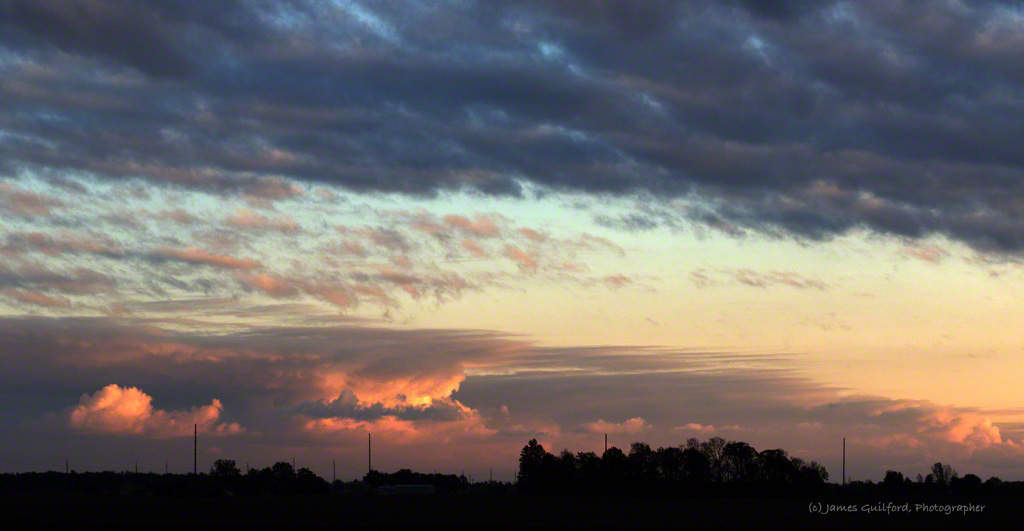 Photo: Sunset-illuminated clouds over rural fields. Photo by James Guilford.