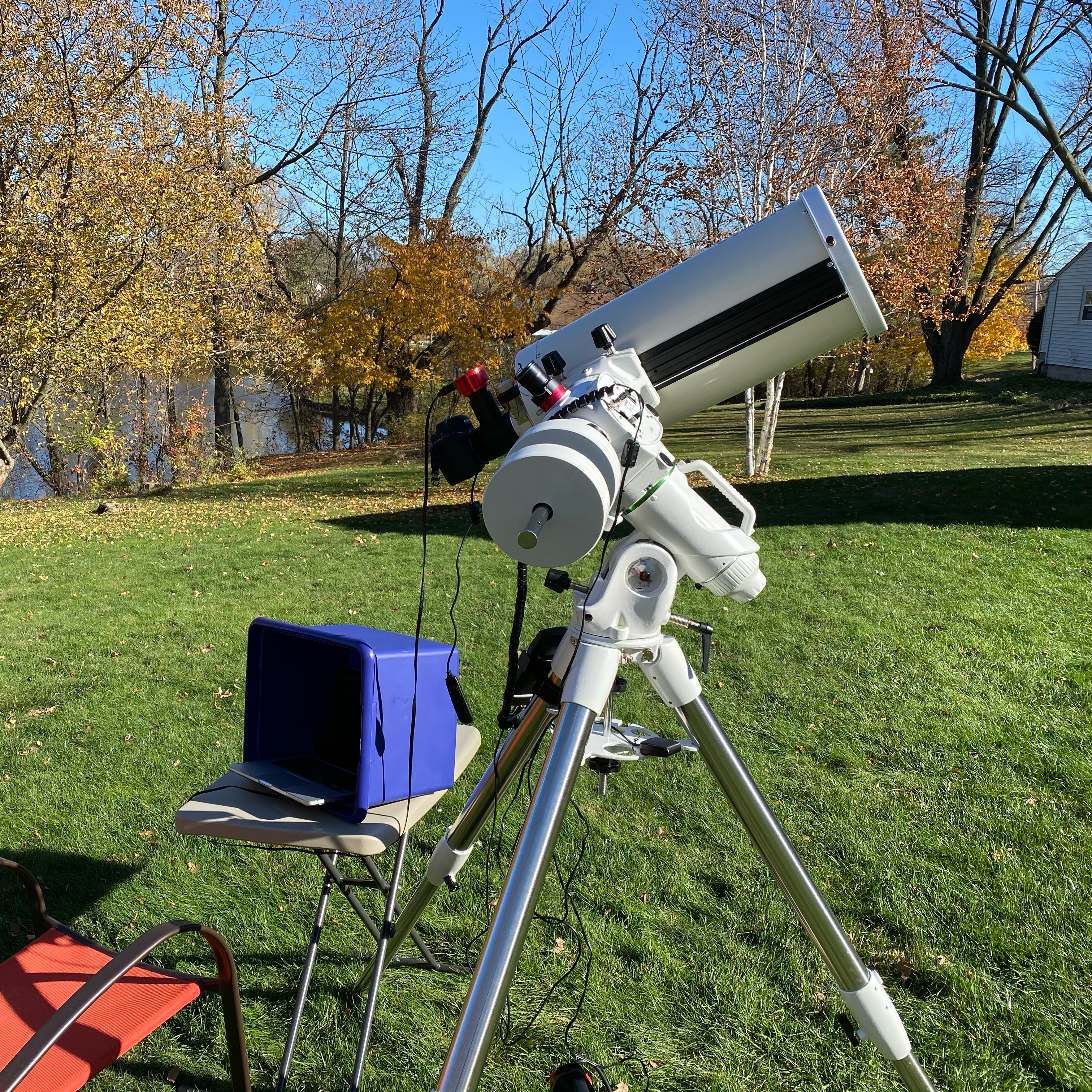 Photo: Telescope set up for solar imaging. The Canon EOS 6D Mk. 2 camera is in silhouette at the base of the scope while the little red ASI planetary camera rides above it. The blue box shades a laptop computer for use with the ASI.